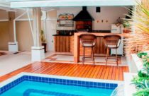 Ambiente com Deck de madeira - Deck de madeira separando a piscina da área com churrasqueira